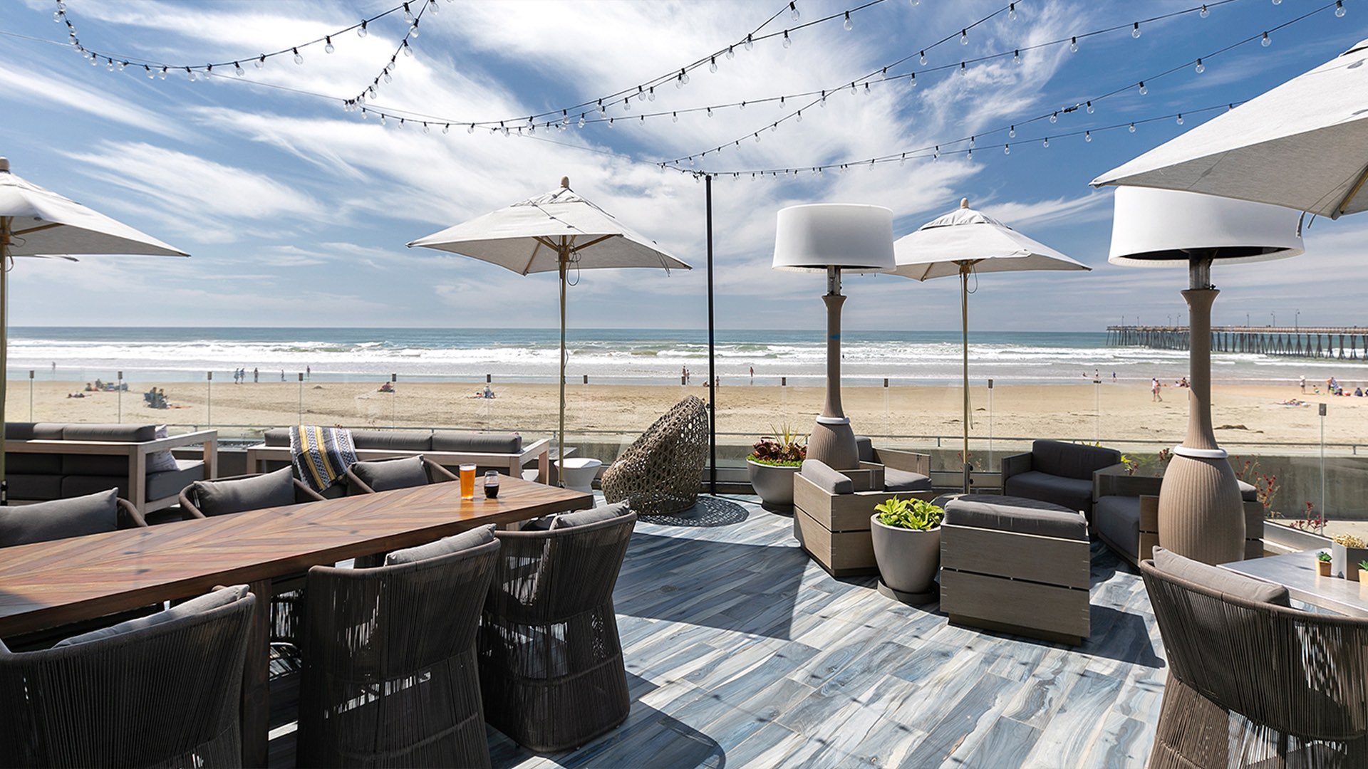 A beachside outdoor patio with furniture and a view of the ocean.
